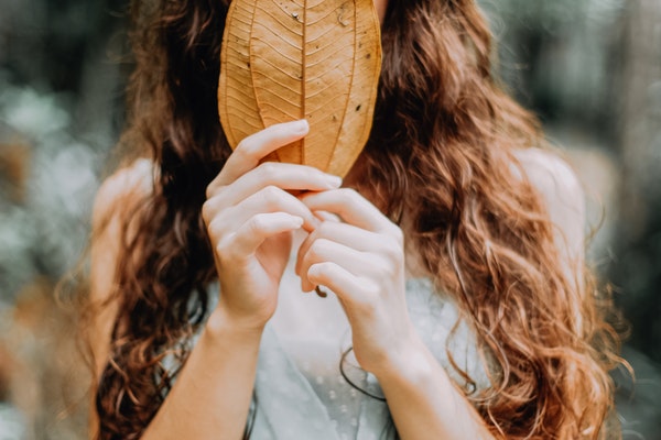 woman-covering-her-face-with-a-brown-leaf-3198026